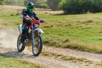 A professional motocross rider exhilaratingly riding a treacherous off-road forest trail on their motorcycle.