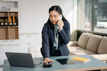 Asian woman sitting at a desk using a laptop computer Navigating Finance and Marketing with...