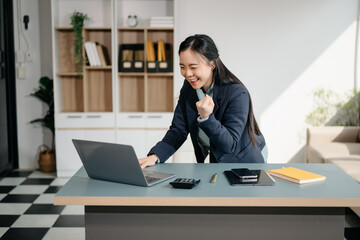 Asian business woman are delighted and happy with the work they do on their tablet, laptop and...