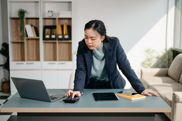 Business woman using tablet and laptop for doing math finance on an office desk, tax