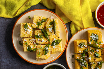 Famous Gujrati snack Dhokla made with gram flour and sugar syrup decorated with mint and tomato...