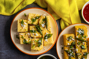 Famous Gujrati snack Dhokla made with gram flour and sugar syrup decorated with mint and tomato chutney. 