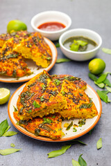 Gujrati food handvo decorated with mint chutney, curry leaves, lemons and tomato sauce. selective focus. 