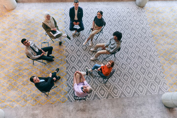 Top view of a diverse group of young business entrepreneurs gathered in a circle for a meeting,...