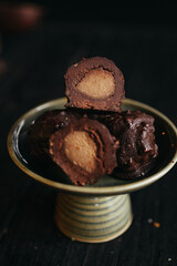 A still life of chocolate truffles with liquid filling at dark background