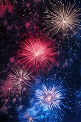 Fototapeta premium A fireworks display with red, white, and blue fireworks. The fireworks are lit up in the night sky, creating a festive and celebratory atmosphere