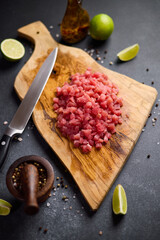 Sliced and chopped tuna fillet on wooden cutting board at domestic kitchen cooking traditional tartare