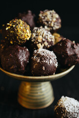A still life of assorted chocolate truffles on the plate at dark background