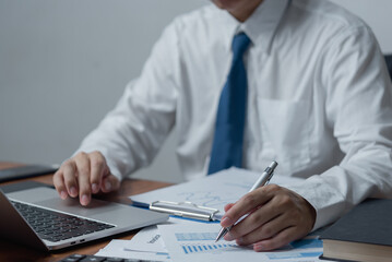 businessman holding pen to analyze data, graphs and market reports of business and growth trends.