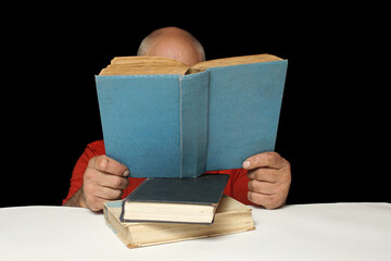 A man is reading a large blue-bound book holding it in front of him.