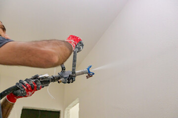 Worker is applying skim coating material to the wall before painting