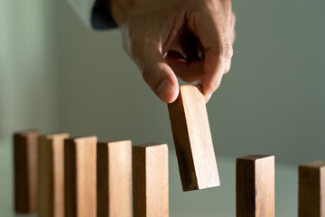 insurance with hands protect domino. Businessman hands stop dominoes falling in business crisis....