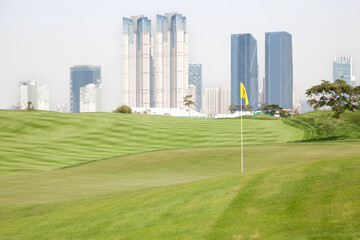 Obraz premium View of the green golf course against the skyscrapers