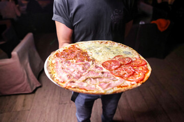 Man Holding a Pepperoni and Mushroom Pizza