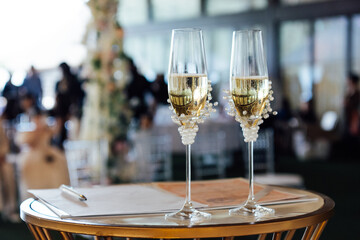 Two wedding glasses stand on a stand against the backdrop of the ceremony arch.