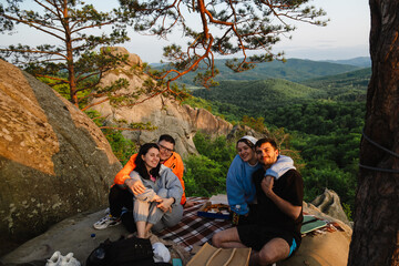 happy friends eating pizza at the cliff with beautiful mountain view