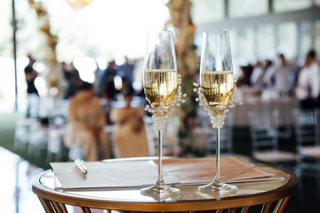 Two wedding glasses stand on a stand against the backdrop of the ceremony arch.
