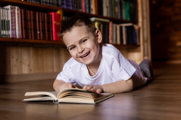 little boy is reading a book in the library at home