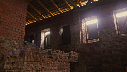 An old ruined building with broken walls and boarded up windows windows. Stock footage. View inside of a large industrial brick wall building.