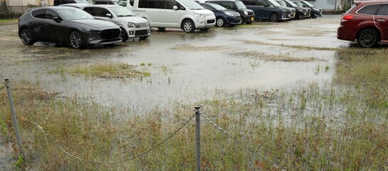 雨で水溜りができた自動車の駐車場