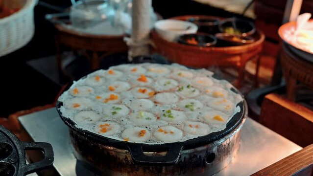 4K Close-up of woman's hand cooking traditional Thai street food coconut-rice pancakes.Khanom Khrok  is a traditional Thai dessert.