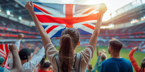 Cheering crowd at a football stadium. A fan waves the Union Jack flag, showing support and excitement during a thrilling match.
