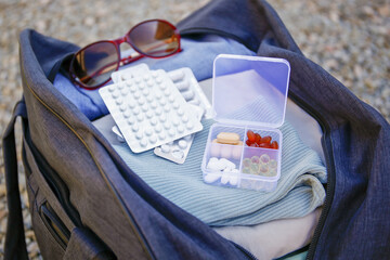 Clothes and pills in a travel bag. Concept of medication required in journey