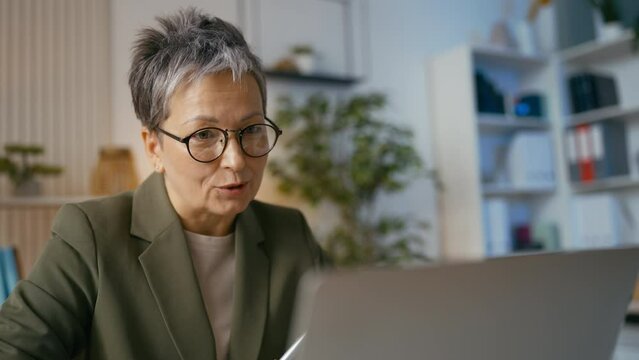 Happy middle-aged female CEO having online video call with a business partner