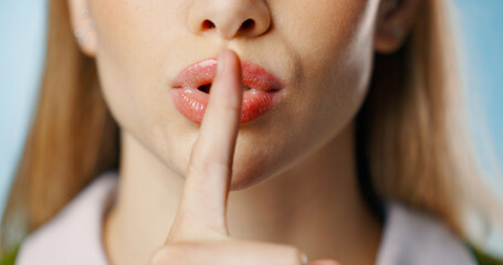 Woman, finger and lip in studio for secret, news and gossip for privacy with hand gesture for announcement on blue background. Silence, whisper emoji and confidential information, shush and mystery