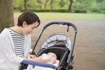 A baby in a stroller and a mother giving milk