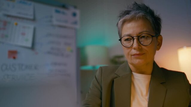 Middle-aged woman accountant typing on laptop in office, working long hours