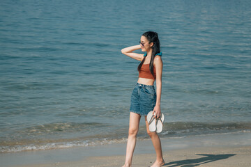 young tourist woman walking along the beach shore