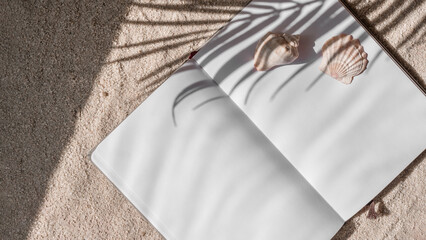 Blank paper open notepad on beach sand background with ocean shells and palm tree leaf sun sight shadows, summer backdrop with copy space