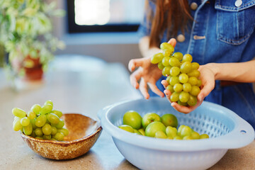 Woman holding bowl of green grapes in front of another bowl of green grapes, healthy fruit concept