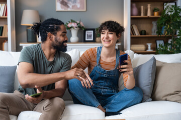 Obraz premium Young couple at home have a problem and argue due to jealousy caused by chatting and flirting via social media networks on smart phones, relationship difficulties problems and distrust