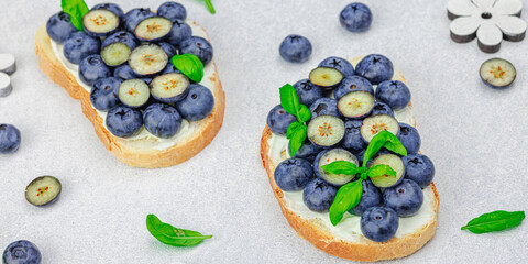 Fresh bread sandwiches with sweet blueberries, cream cheese and basil leaves. Good morning concept
