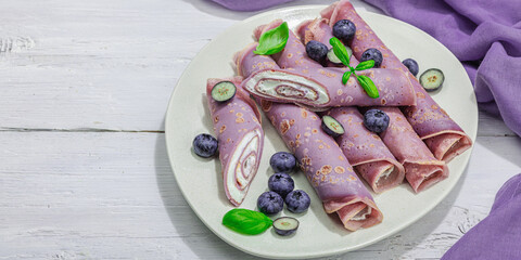 Thin purple pancakes with cream and blueberries. Healthy vegan non lactose and gluten free food
