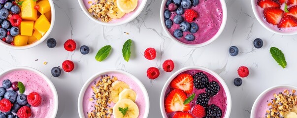 Various smoothie bowls with vibrant fruits and colorful toppings arranged on a white backgrou