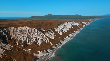 Aerial view of yellow grass field and beautiful rock formations. Clip. Sea shore and cliff.