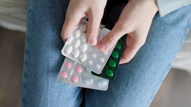 Top view close up tablets of different shapes in package, in hands of human unrecognizable.