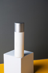 Plastic white tube for cream or lotion. Skin care or sunscreen cosmetic on grey and yellow background.