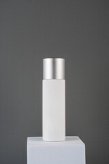 Plastic white tube for cream or lotion. Skin care or sunscreen cosmetic with stylish props on grey background.