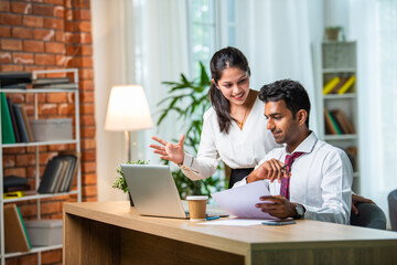 Indian asian young CEO businessman working with female colleague in the office using laptop computer
