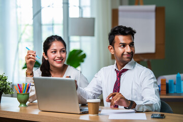 Fototapeta premium Indian asian young CEO businessman working with female colleague in the office using laptop computer