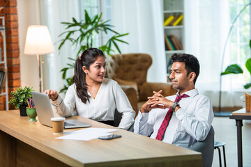 Indian asian young CEO businessman working with female colleague in the office using laptop computer