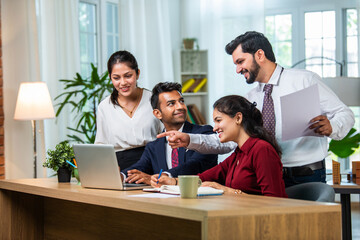 Indian young businesspeople using laptop in group meeting at desk