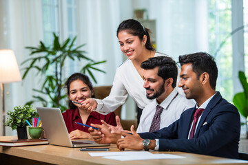 Indian young businesspeople using laptop in group meeting at desk