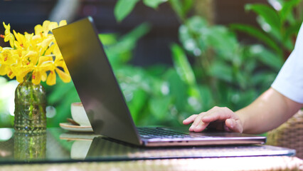 Closeup image of a woman working and typing on laptop computer keyboard in the outdoors