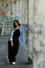 Attractive Caucasian young woman brunette hippie in casual clothes posing on the grounds of an abandoned building while walking on a warm spring day. Style, Fashion, Freedom.