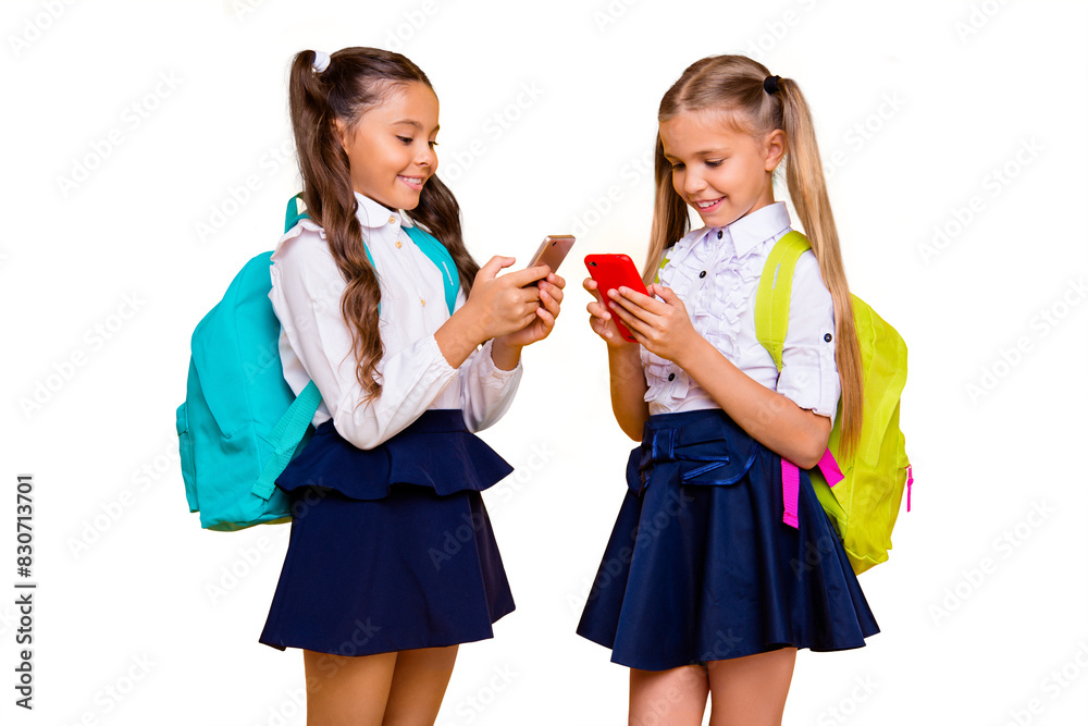 Canvas Prints Profile side view photo of two happy and focused small girls in skirts isolated on bright yellow background with smartphones in their hands read interesting news